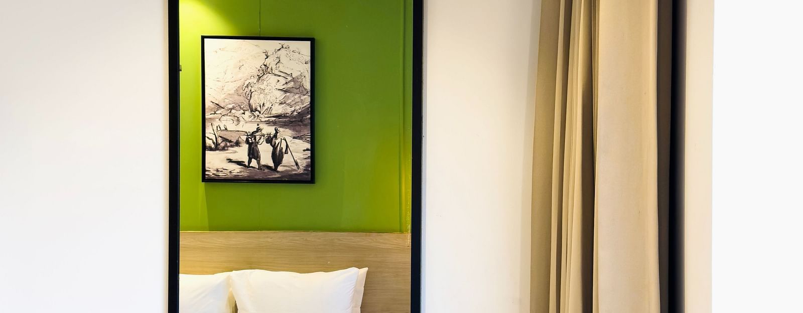 A wall-mounted mirror showcasing the reflection of the bed in the room - Wonder Hills