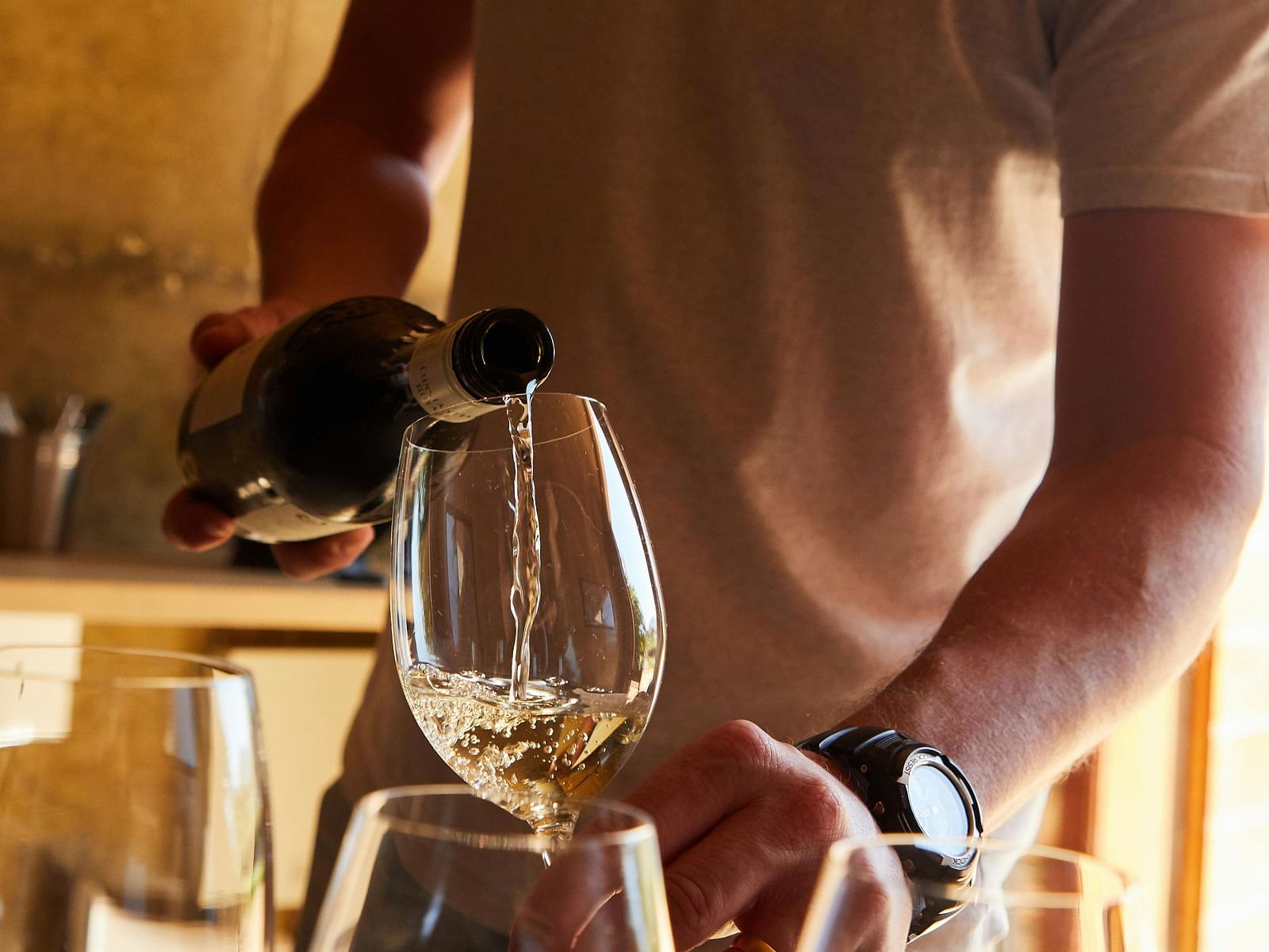 a man pouring white wine into a glass from a wine bottle