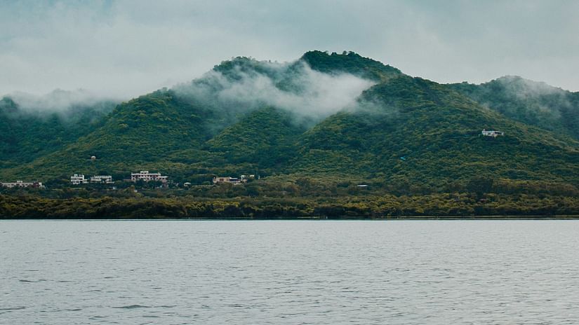 A view of a large waterbody with a mountain having a cloud cover in the far distance 