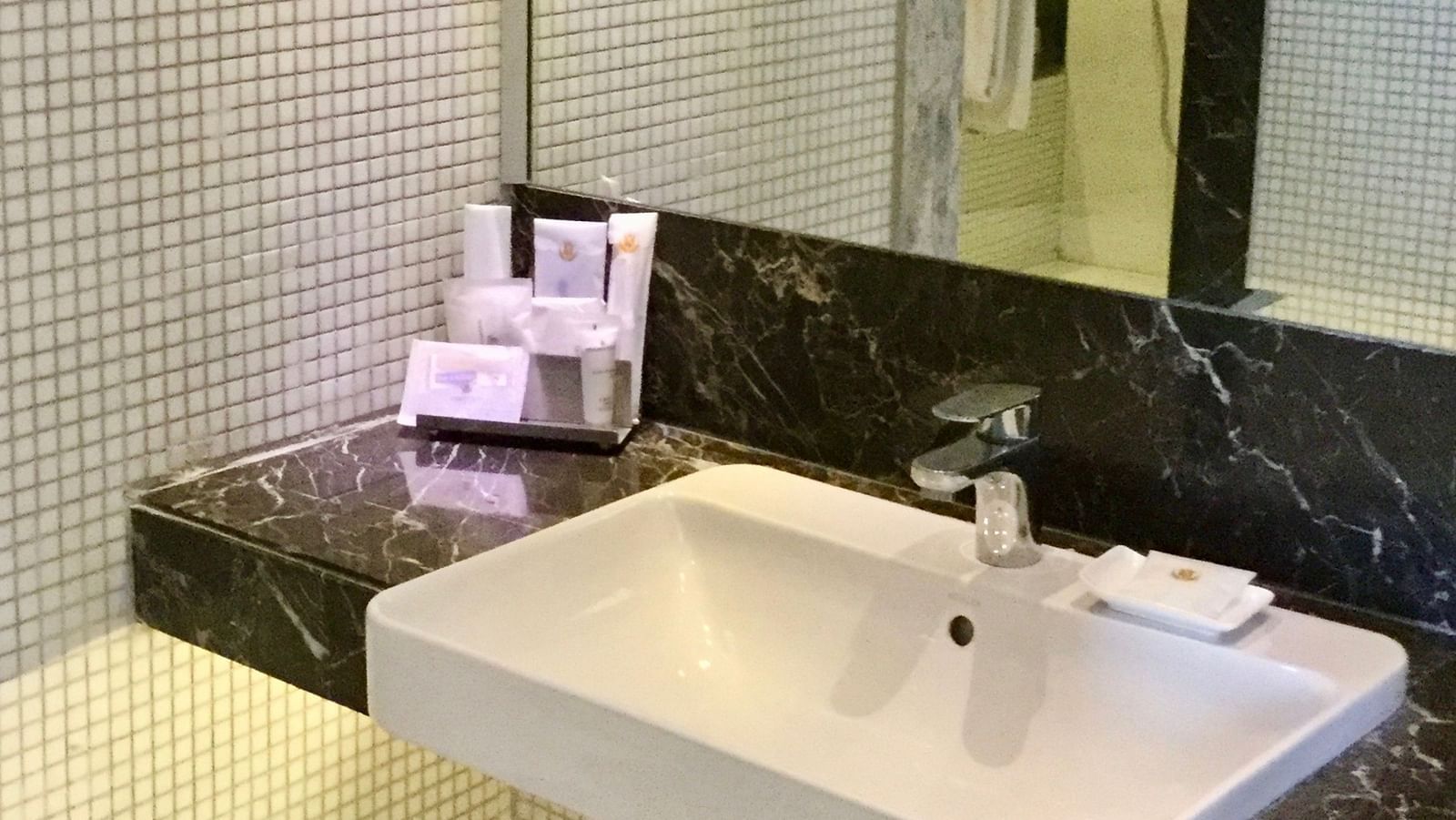 A wash basin with bathroom essentials kept besides it along with a huge mirror above the basin - Ramada by Wyndham, Ghaziabad, Vasundhara