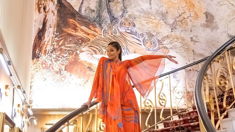 An image of a woman in orange dress walking down the stairs - The Claridges New Delhi