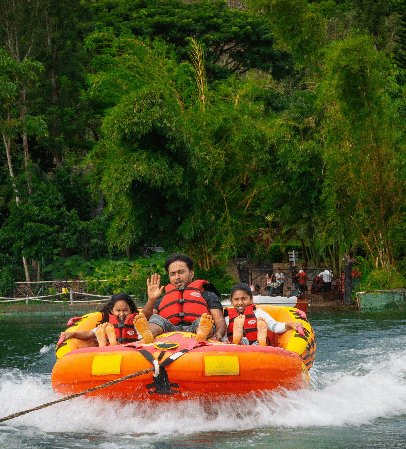 Image of a man and two girls on a boat with trees in the background.