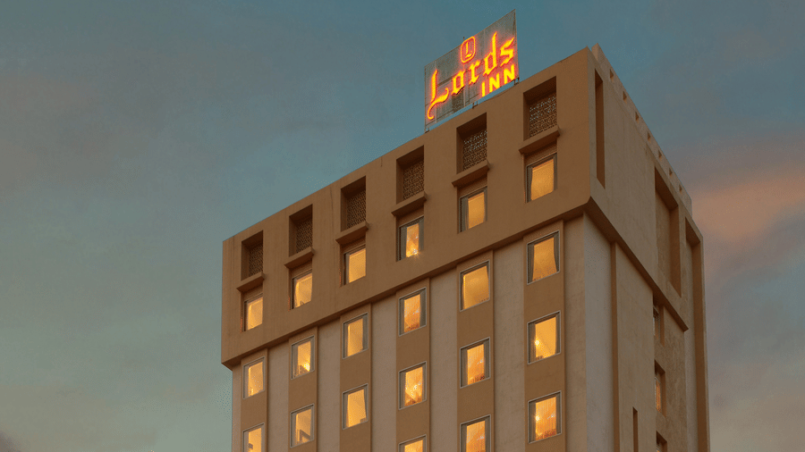 A facade of Lords Inn Jodhpur building with dimly lit lights in rooms and sky behind it