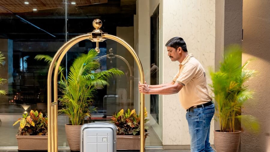 Hotel staff member pushing a luggage cart at Pravasa Hotel | Pravasa Hotel, Vijayapura