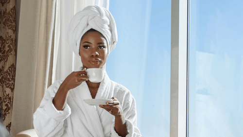 A woman drinks tea dressed in a bathrobe