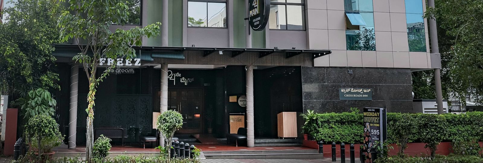 A daytime view of our hotel facade surrounded by greenery - Cross Roads Inn, Bengaluru