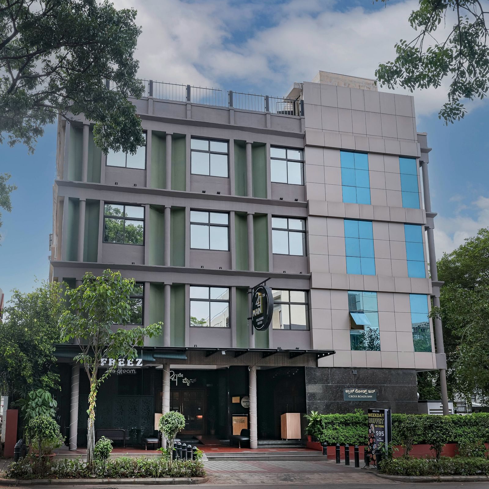 A daytime view of our hotel facade surrounded by greenery - Cross Roads Inn, Bengaluru