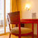 Hotel room seating nook at Featherlite Evoma Hotel with a wooden table and chairs beside a large window overlooking greenery outside it.