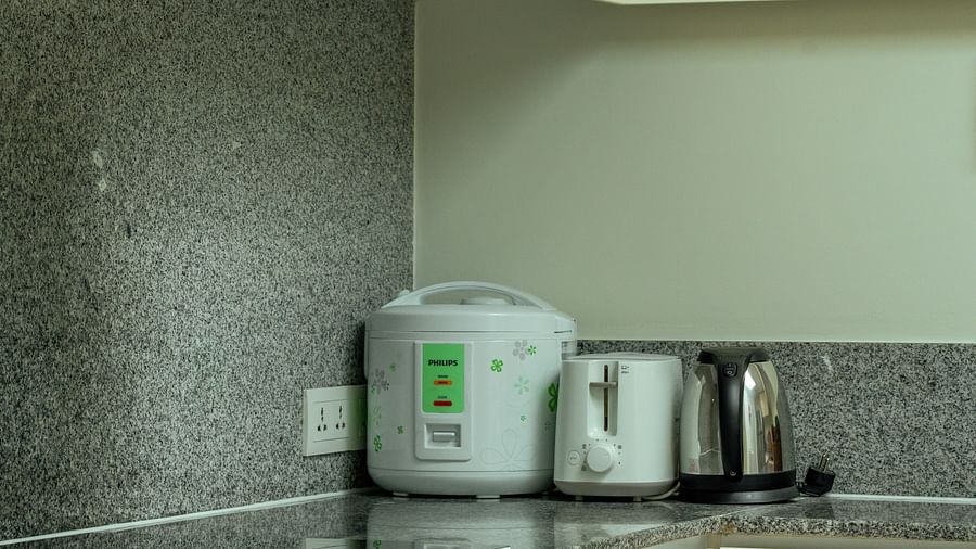 A modern kitchen with white cabinets, a stainless steel stove, and a rice cooker on the counter | Penthouse | Central Mansions, Phnom Penh