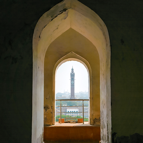View of Lucknow's clock tower framed through a historic architectural archway.
