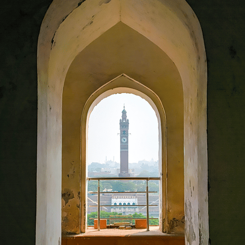 View of Lucknow's clock tower framed through a historic architectural archway.