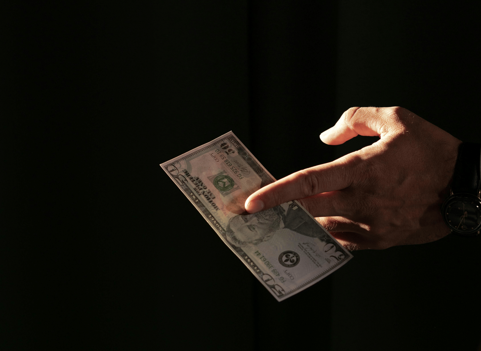 A hand holding a bank note.