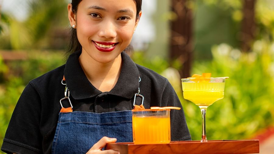 Smiling staff serving mocktails in the glass at The Dukes Retreat with scenic greenery in the backdrop