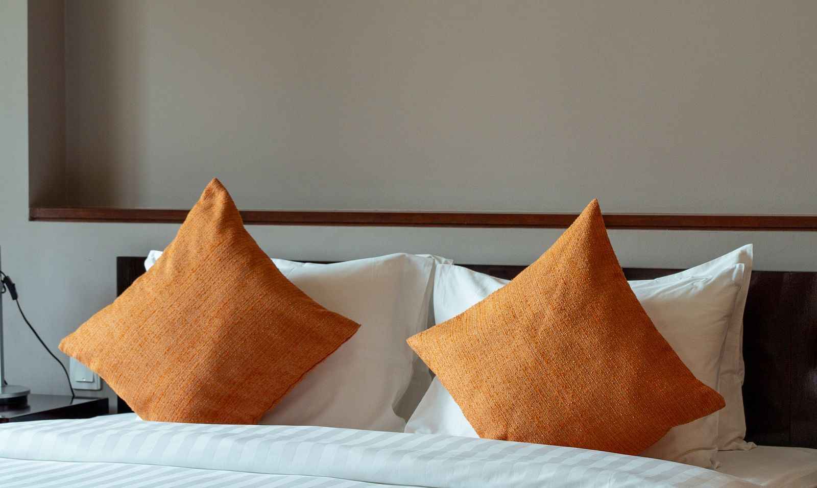 A bedroom with a bed, orange pillows, and a white comforter | Penthouse | Central Mansions, Phnom Penh