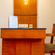 Hotel room desk area at Featherlite Evoma Hotel with a wooden writing desk, a chair and warm ambient lighting along the nearby wall.