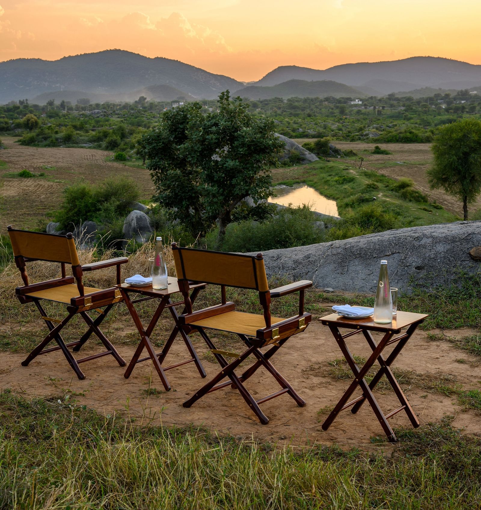 An image of an outdoor seating amidst greenery over viewing the mountains - Utsav Camp Sariska