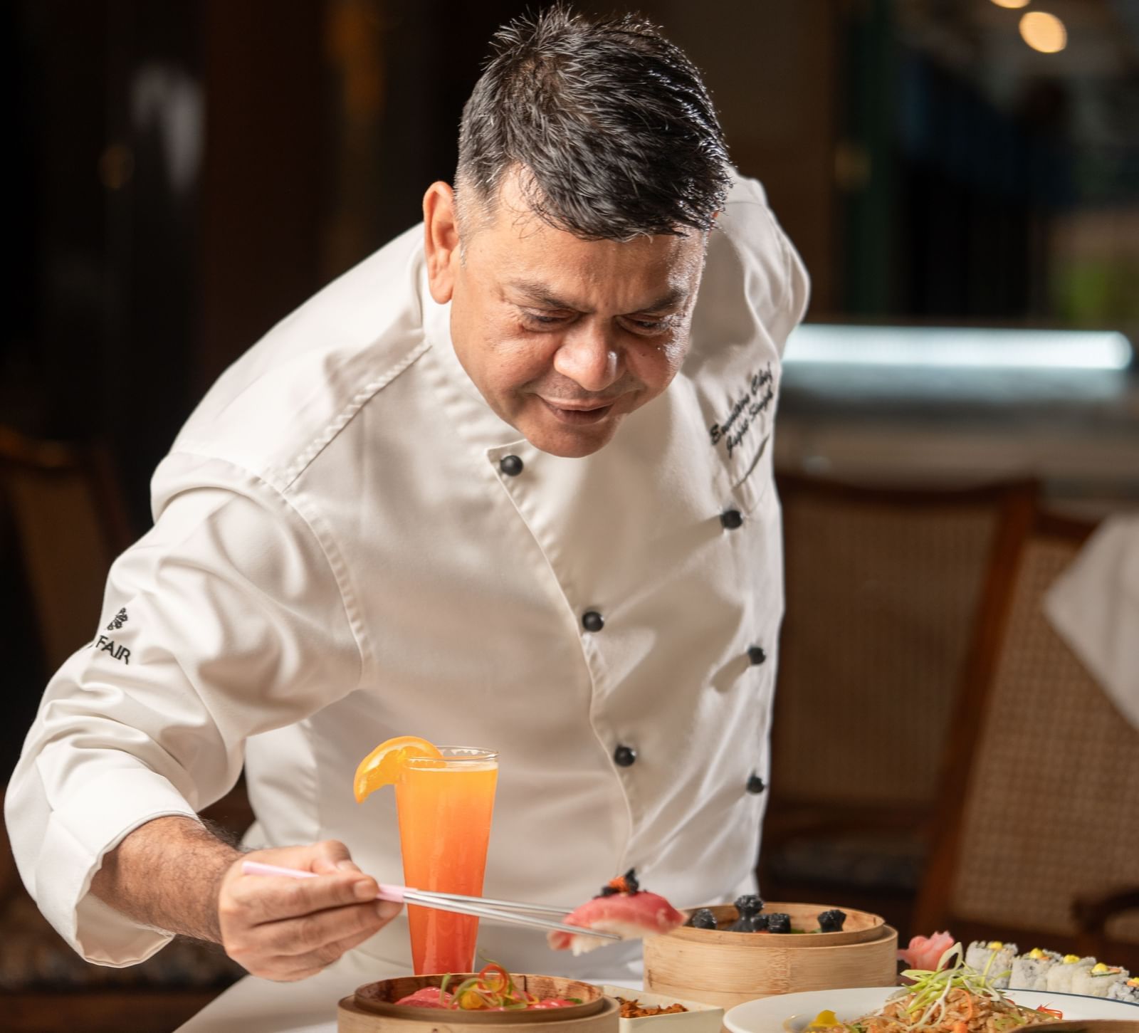 Chef garnishing dessert with an orange sauce