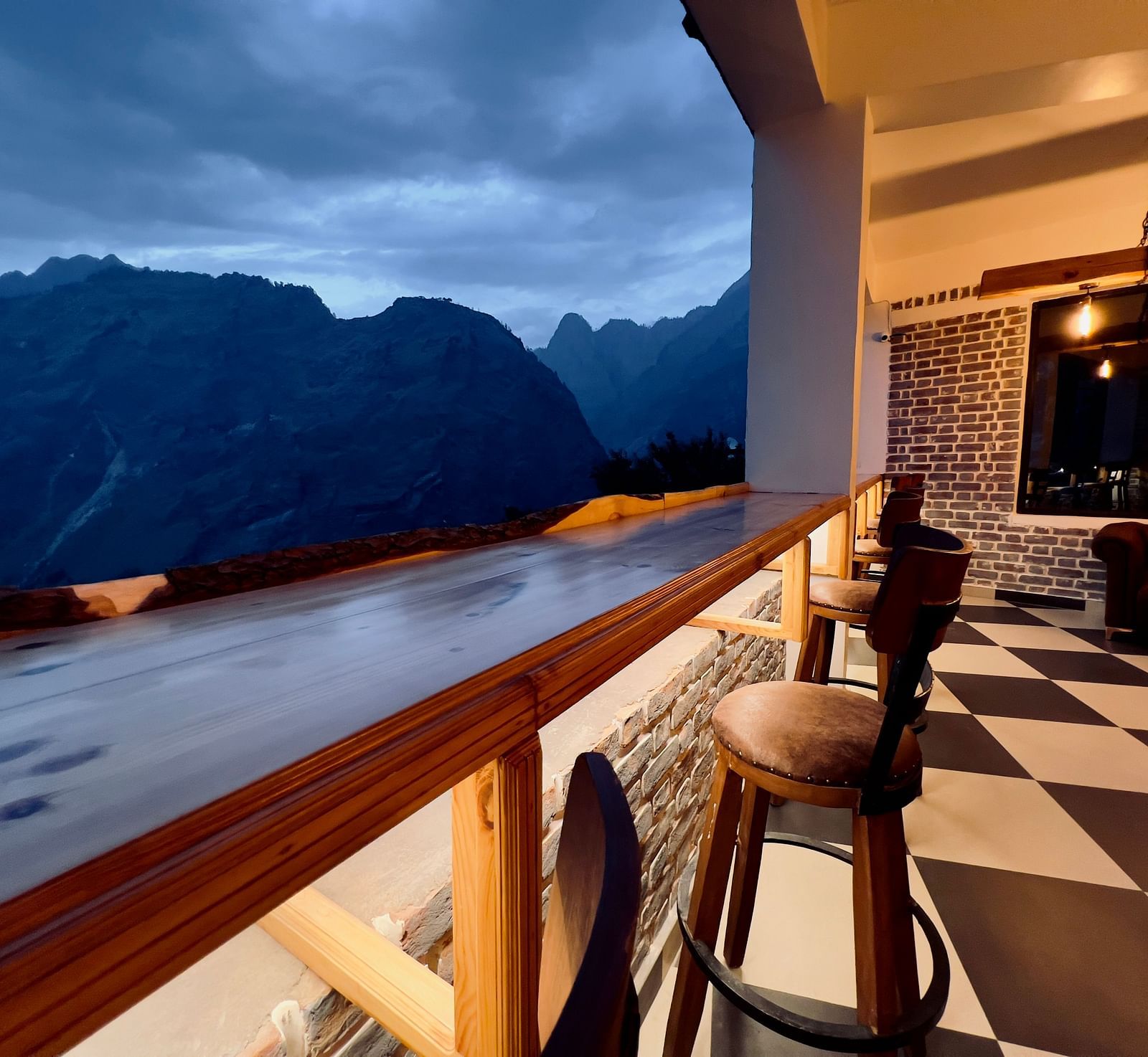image of the bar with black and white titles and elevated chairs overlooking the beautiful mountain ranges in the background - The Tattva Boutique Resort