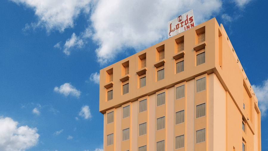 A facade of Lords Inn Jodhpur building with parking and trees adjacent to it