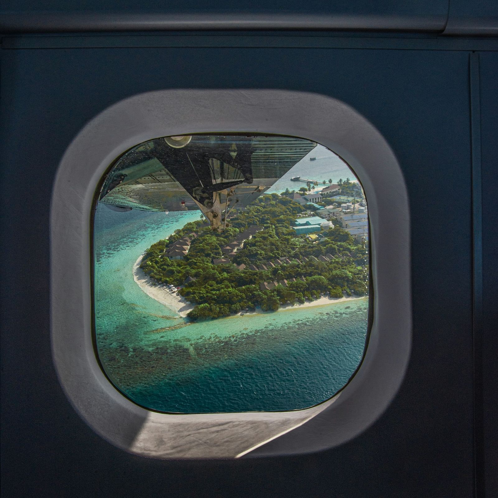 An island seen through an airplane window with water and greenery visible