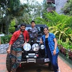 Image of three people standing in front of a car posing for a photo.