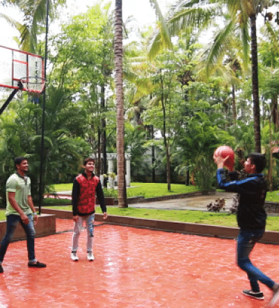 Image of three people playing basketball with trees in the background.