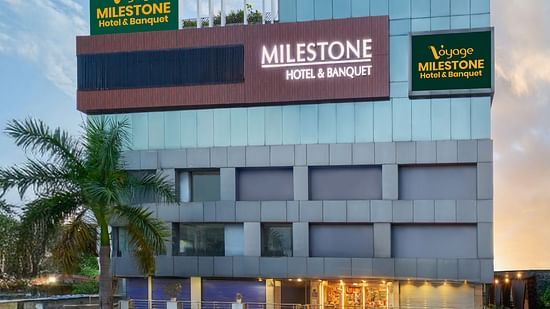 Exterior view of Voyage Milestone Hotel and Banquet in vibrant surroundings, featuring prominent signage and a welcoming façade.