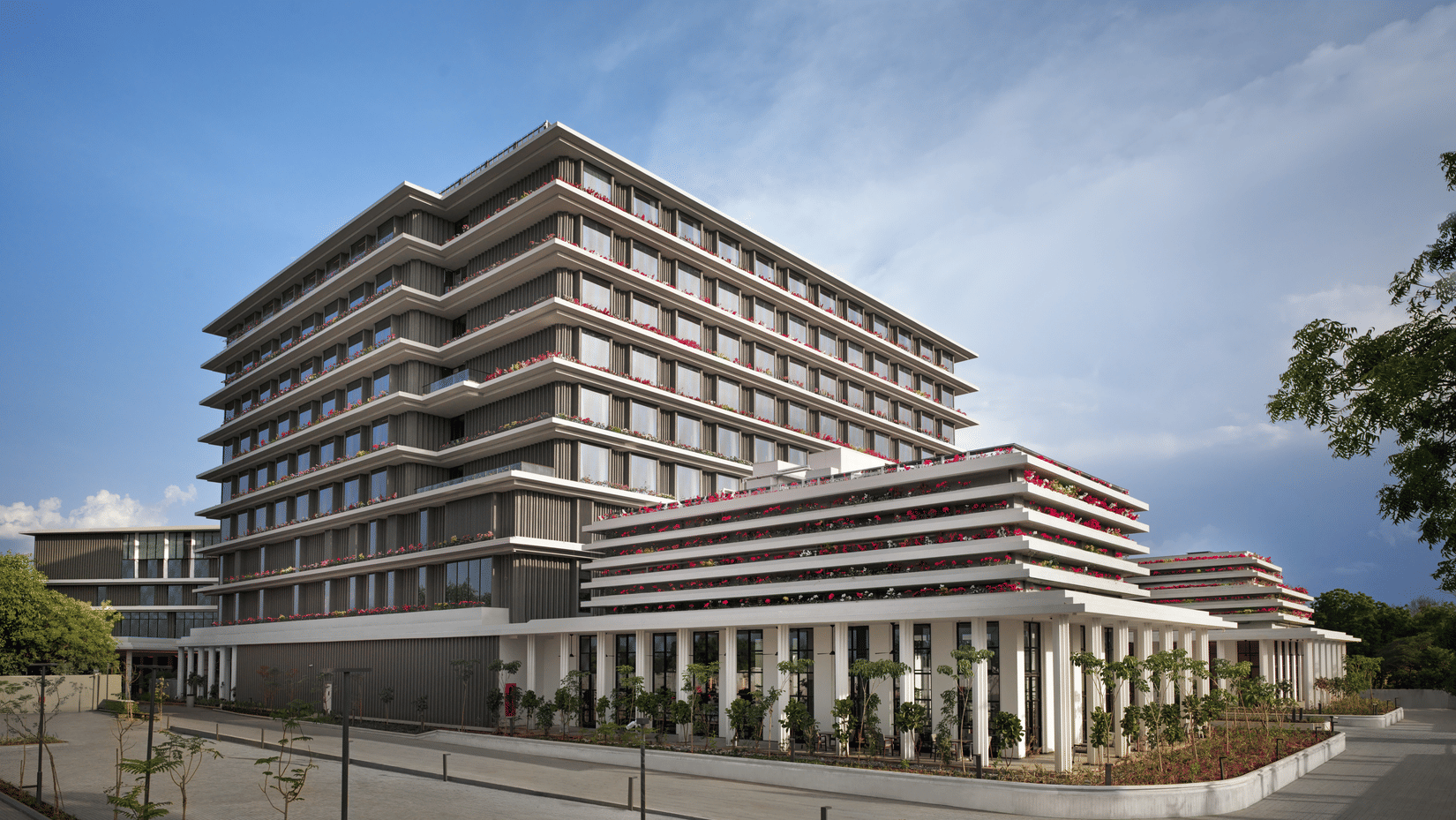 Daytime exterior view of The Residency Signature Madurai with a modern multi-storey facade, manicured grounds, and a bright blue sky.