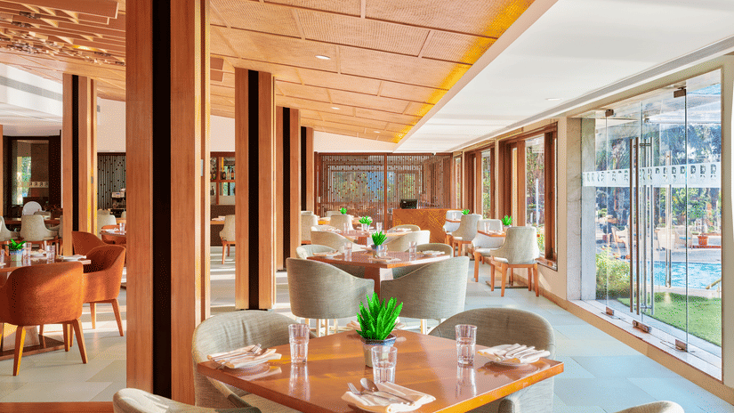 Chairs and tables placed right beside a glass window in a restaurant at The Resort, Mumbai