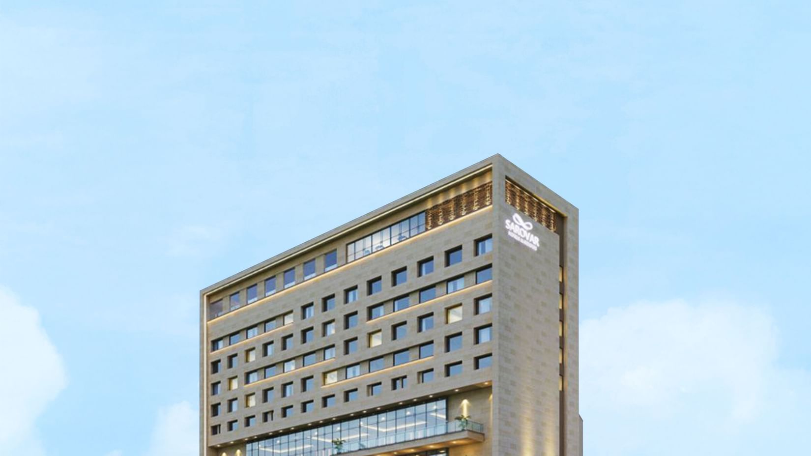 An exterior shot of the Sarovar Premiere Alwar building during the day with a blue sky.