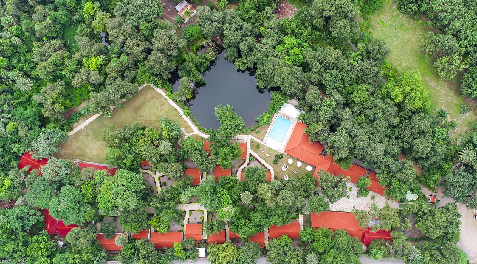 a drone shot of the luxury pond view villa nestled amidst serene greenery at our hotel in udaipur