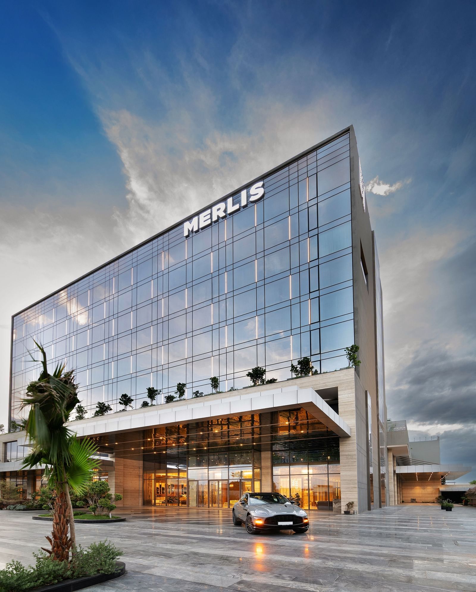 Angular architectural view of the hotel with a sleek glass exterior at Merlis Hotel, Coimbatore.