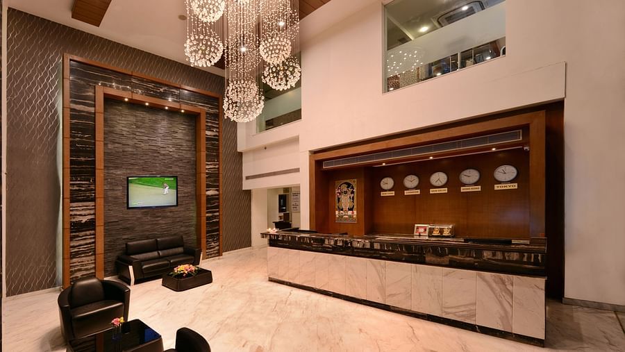 A hotel reception with a big chandelier, sofa and a table 