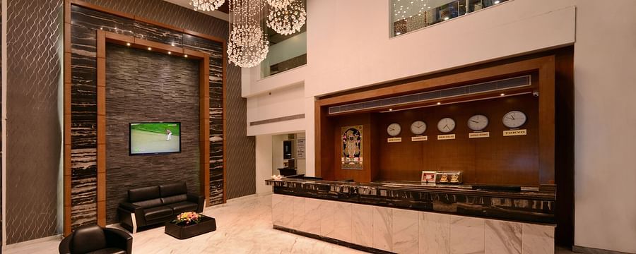 A hotel reception with a big chandelier, sofa and a table 