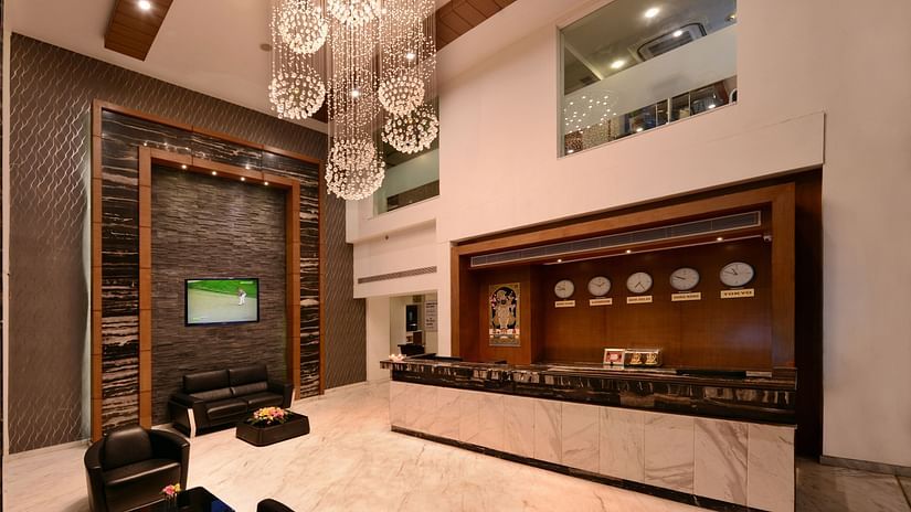 A hotel reception with a big chandelier, sofa and a table 