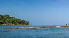 A view of a beach and a land filled with trees in the background
