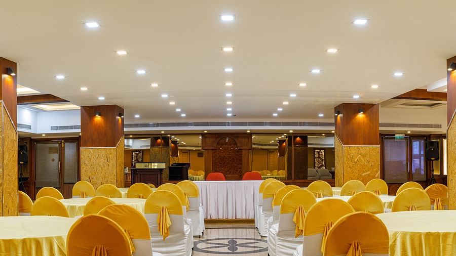 A wide angle image of a Big hall with tables and chairs arranged for dining.