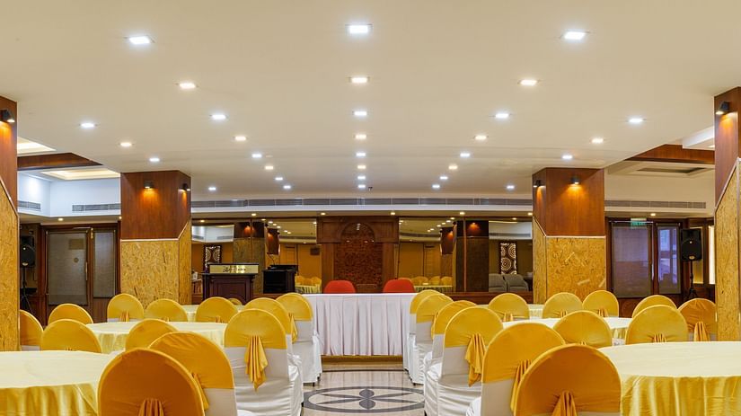 A wide angle image of a Big hall with tables and chairs arranged for dining.