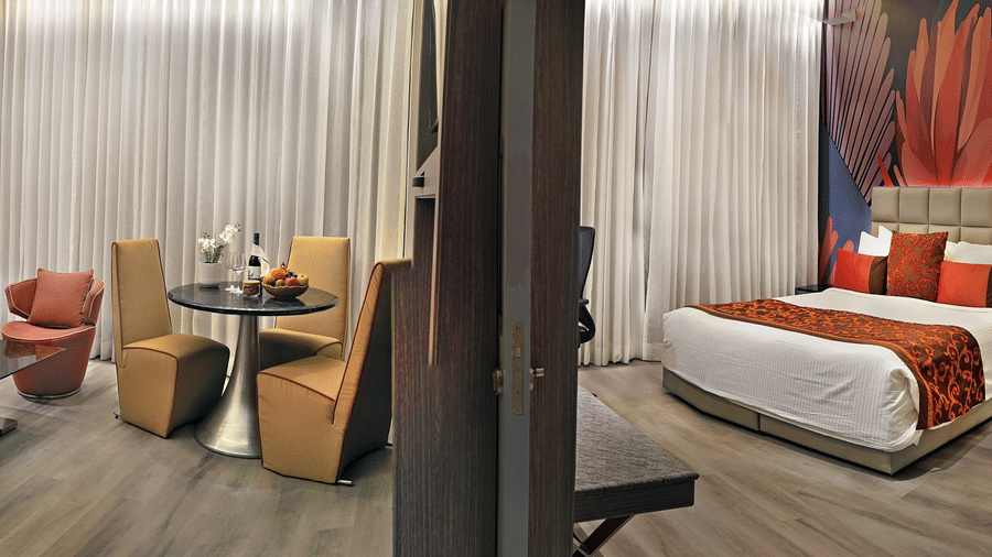 Suite bedroom at The Sonnet, Kolkata with a double bed, bedside tables, seating area and floor to ceiling curtains.