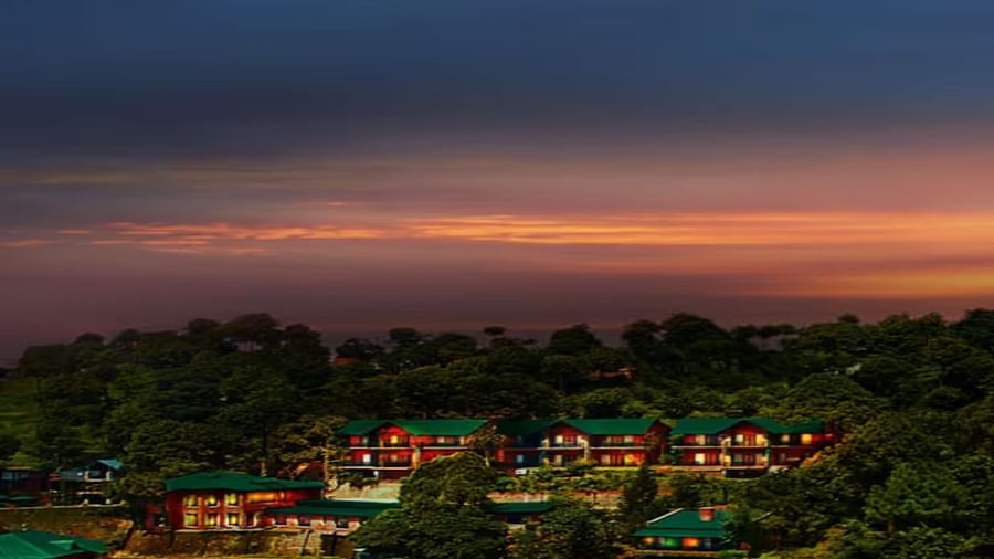 a drone shot of the property taken during the evening with the hotel covered in a dense forest - Baikunth Resort, Kasauli