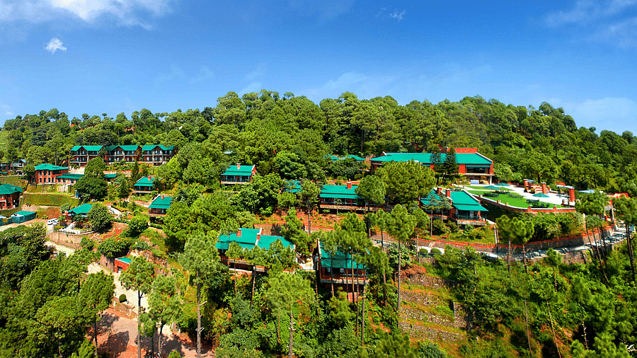 a drone shot of the property with a dense forest surrounding it - Baikunth Resort, Kasauli