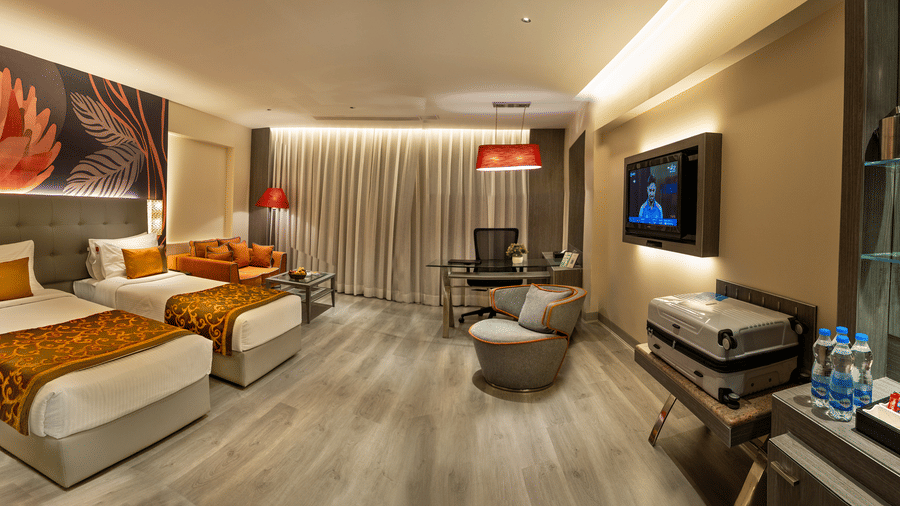 Executive Room at The Sonnet, Kolkata featuring twin beds, a lounge chair, television and seating area.