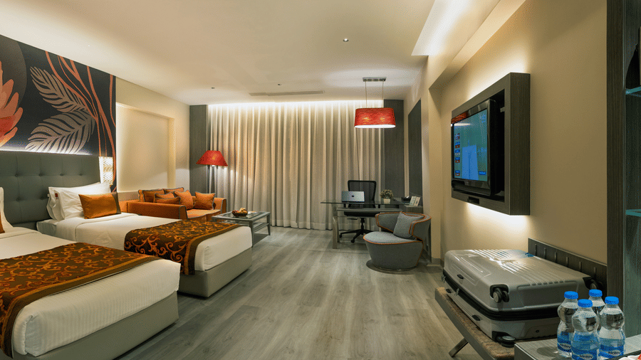 Executive Room at The Sonnet, Kolkata featuring twin beds, bedside tables, television and a seating area.