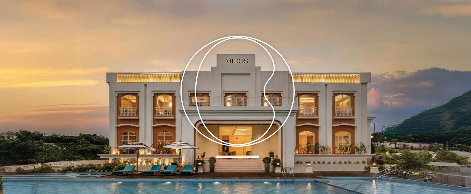 Full view facade of Miros Hotels with a calm swimming pool in the foreground along with beautiful sunset skies in the background.
