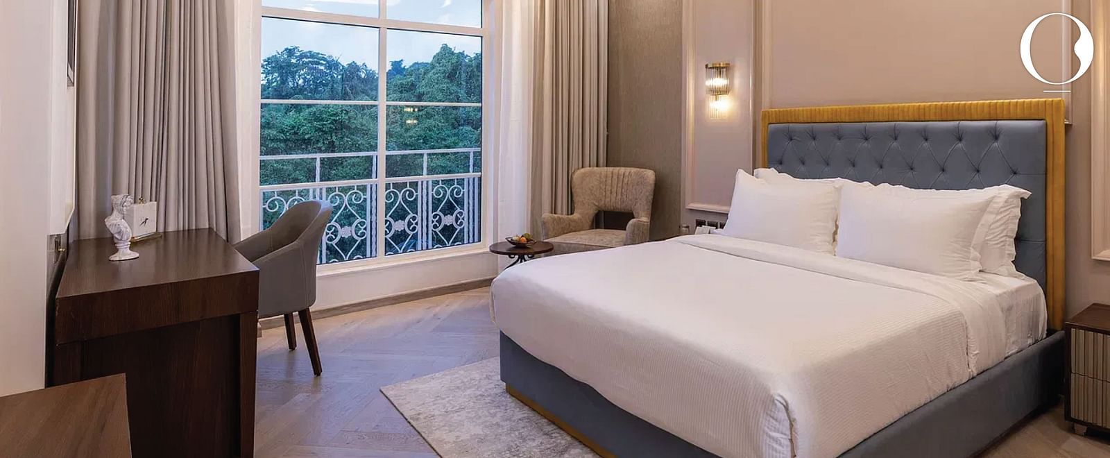 Corner view of the Serene Room featuring a double bed and a chandelier hanging from the ceiling right above it at Miros Hotels..
