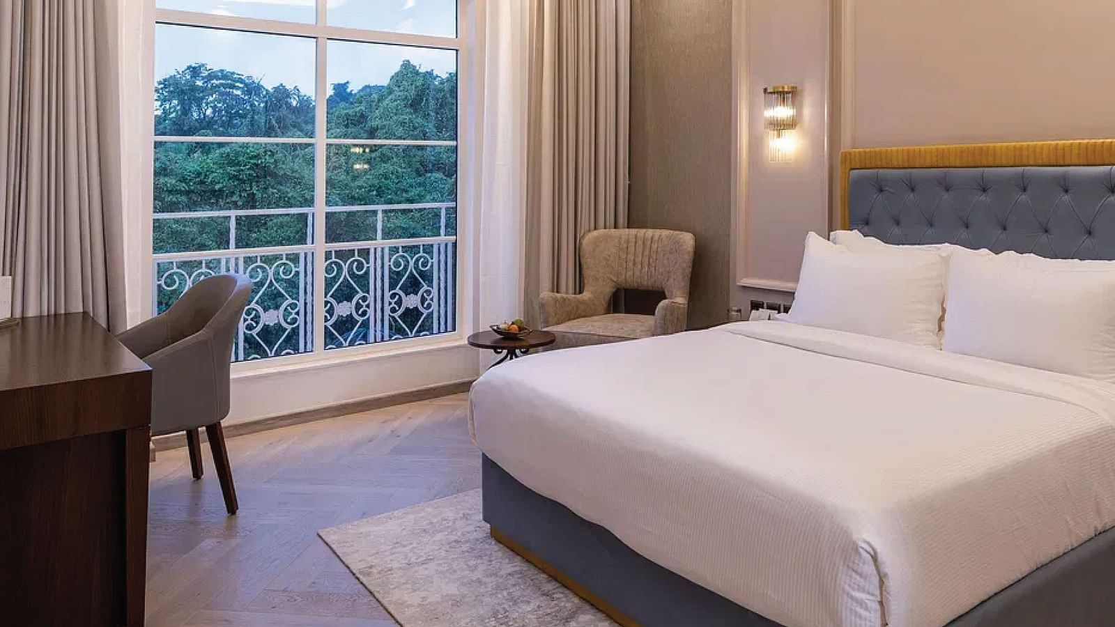 Corner view of the Serene Room featuring a double bed and a chandelier hanging from the ceiling right above it at Miros Hotels..