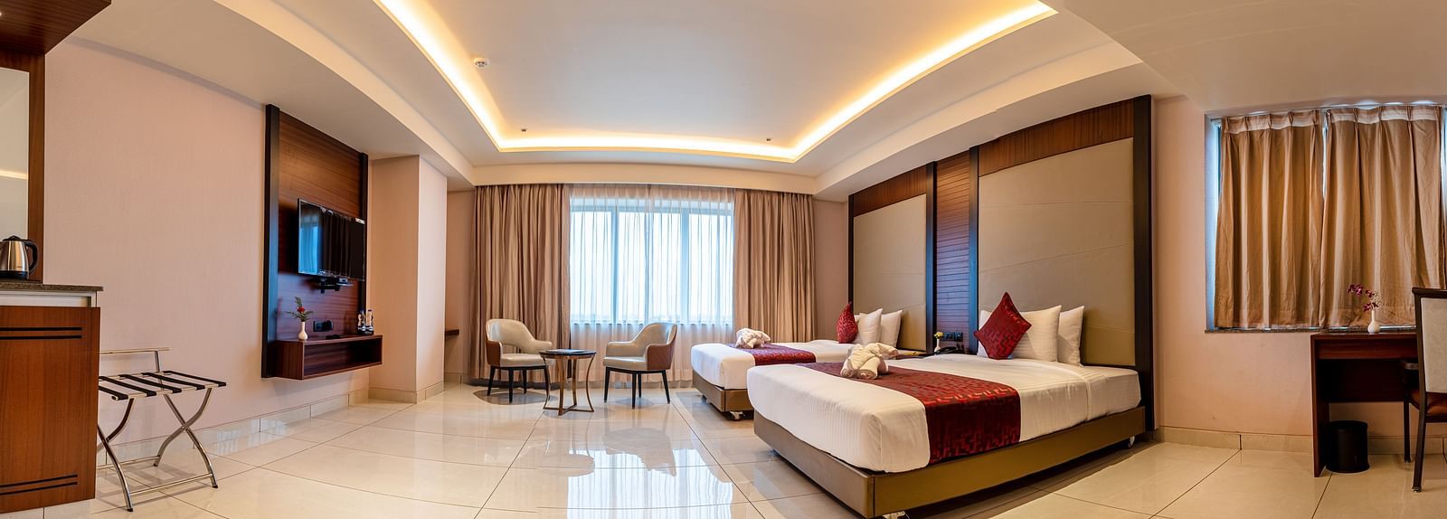 A panoramic view of a room featuring a bed, a seating area, and a television at M Pro Palace.