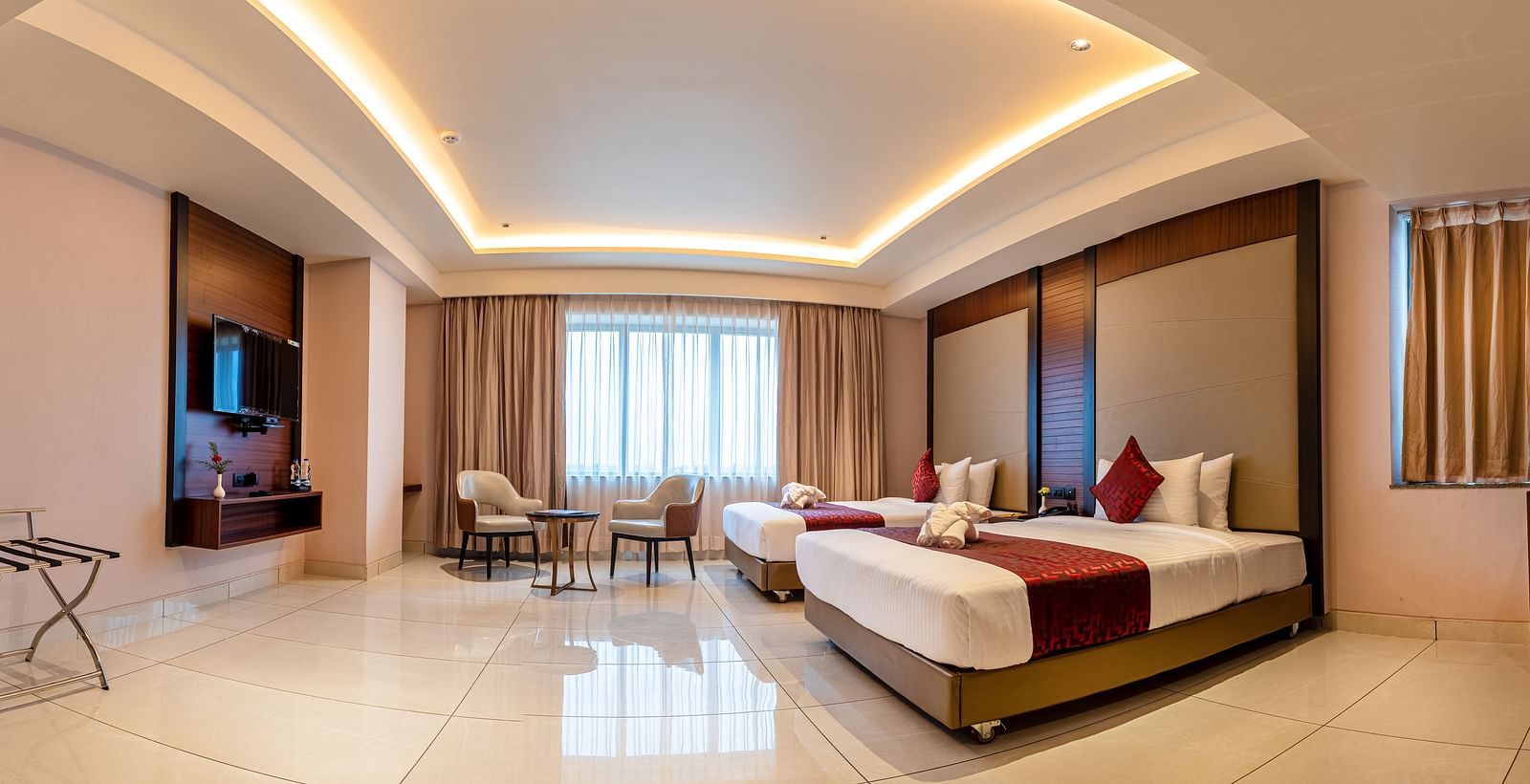 A panoramic view of a room featuring a bed, a seating area, and a television at M Pro Palace.