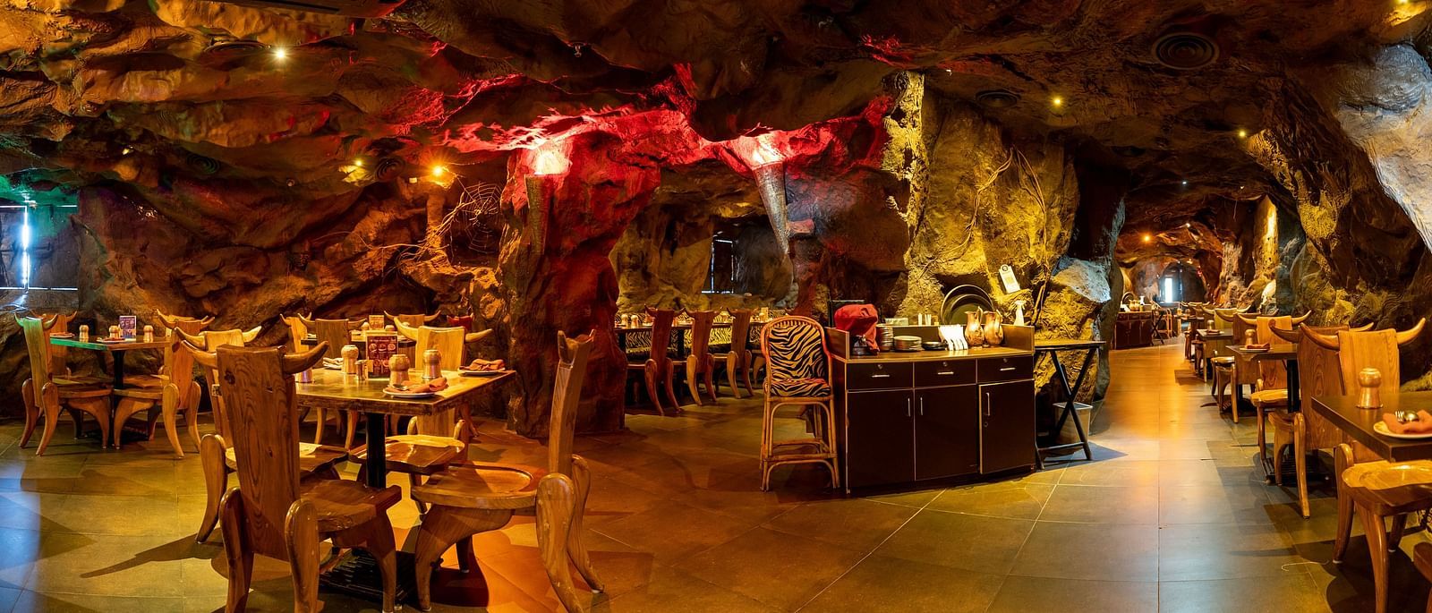 An image of cave themed restaurant with a few sets of chairs and table - The Presidet Hotel, Hubli