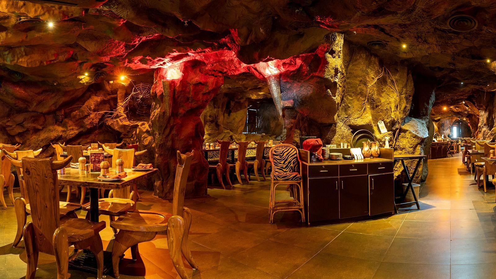 An image of cave themed restaurant with a few sets of chairs and table - The Presidet Hotel, Hubli
